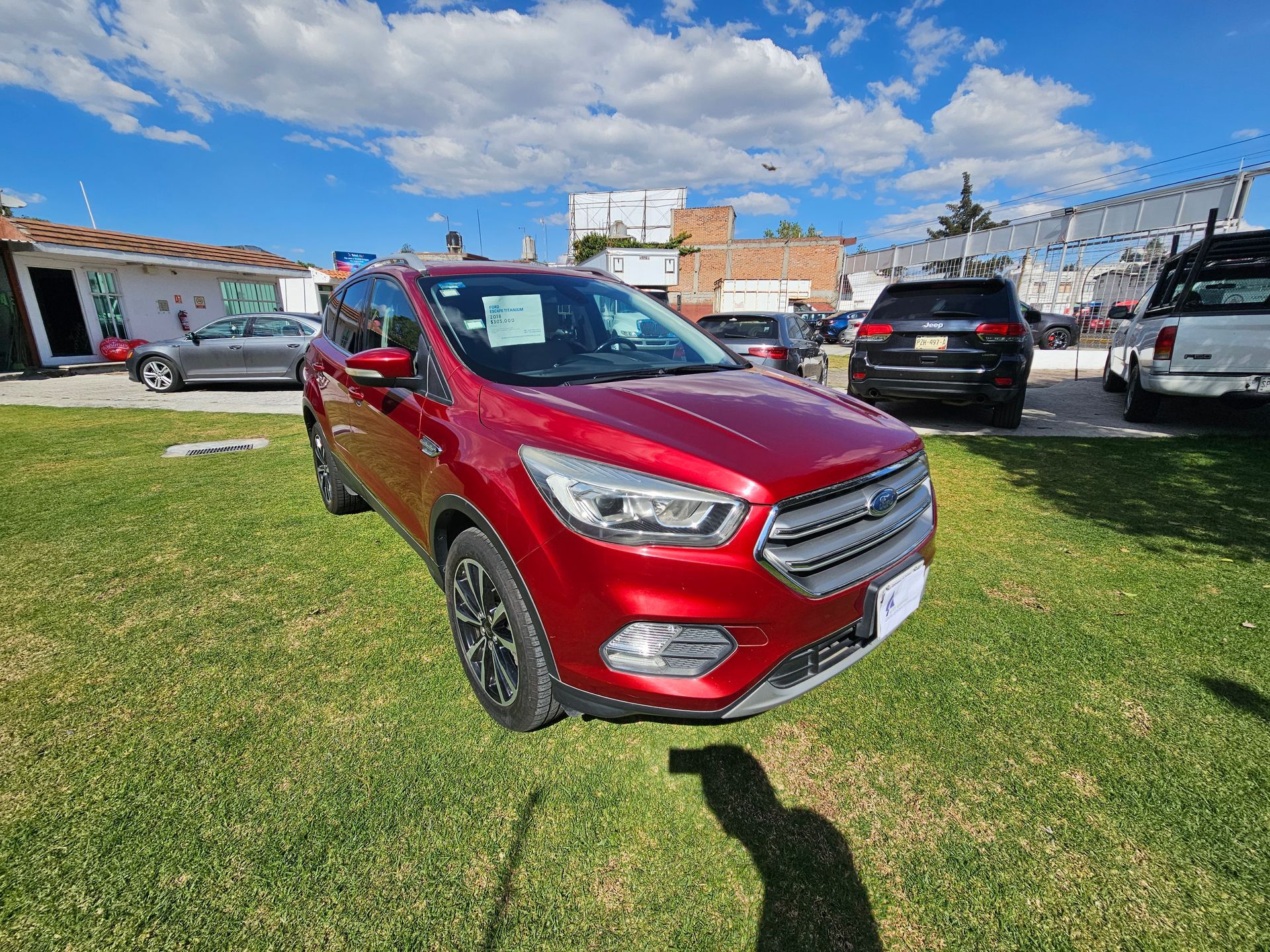 SUV Ford Escape rojo estacionado en el césped al aire libre, día soleado.
