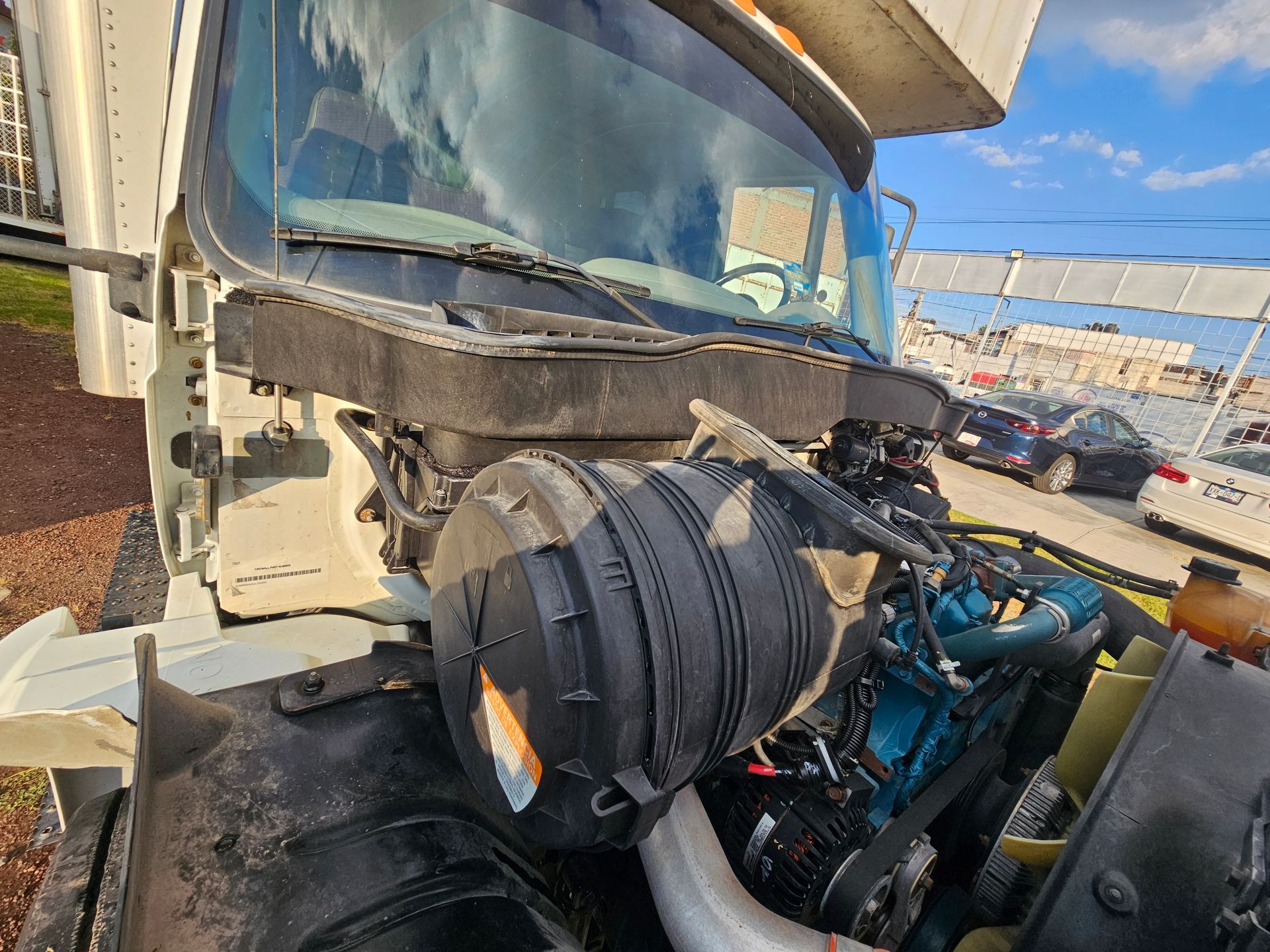 Capó abierto de un camión semirremolque blanco que muestra los componentes del motor y el filtro de aire.