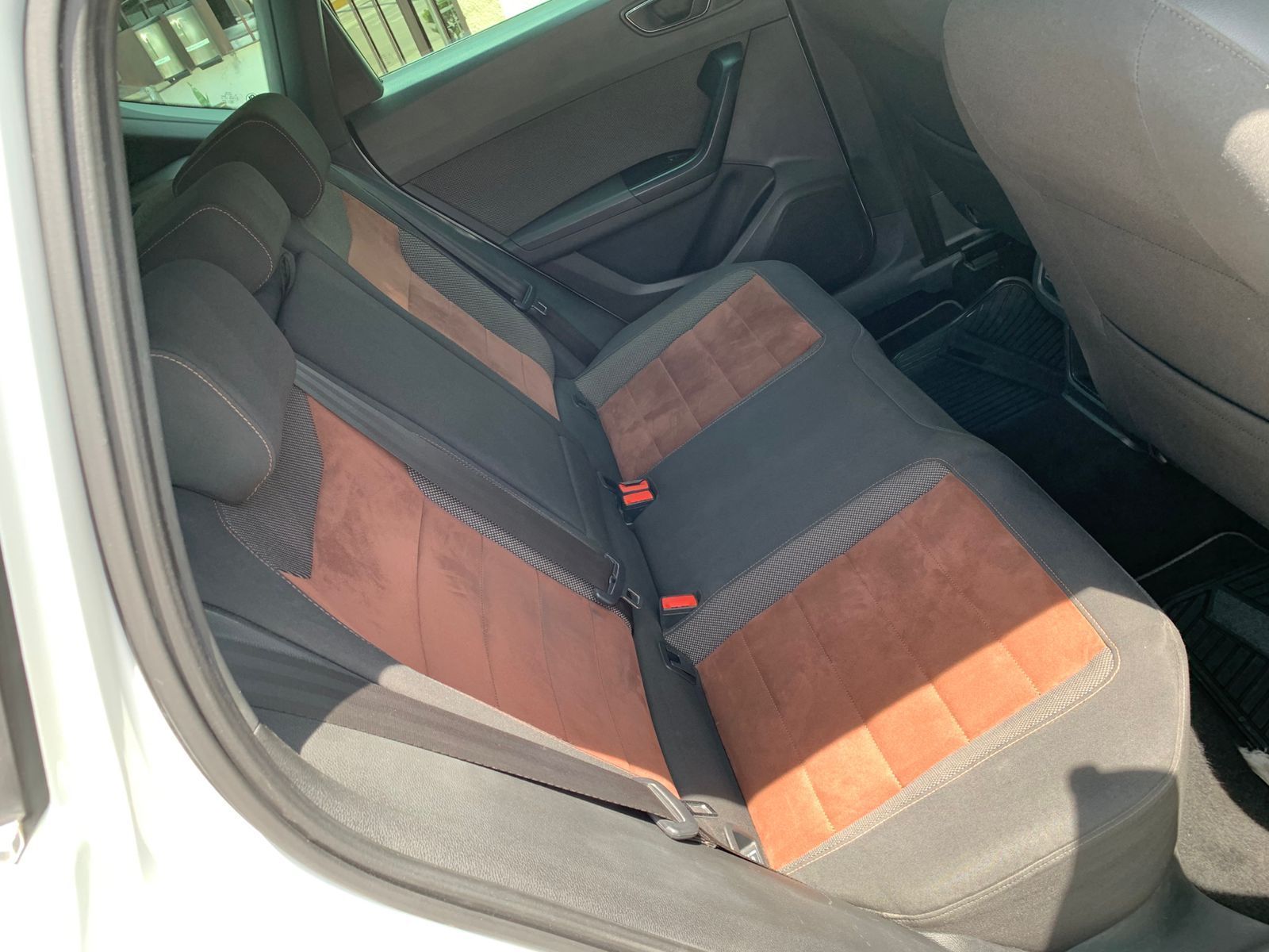 Asiento trasero de un coche con tapizado negro y marrón.