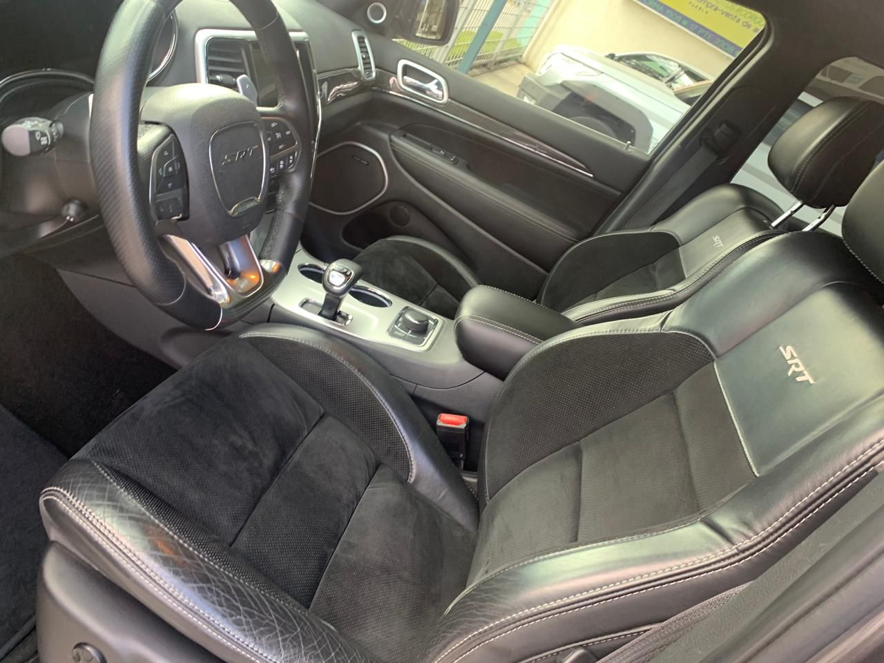 Interior de un Jeep Grand Cherokee SRT negro con asientos, volante y consola de cuero.