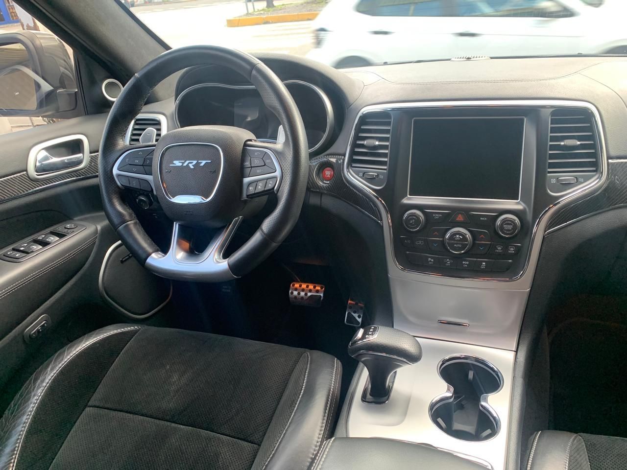 Interior de coche negro con volante, salpicadero y palanca de cambios visibles.