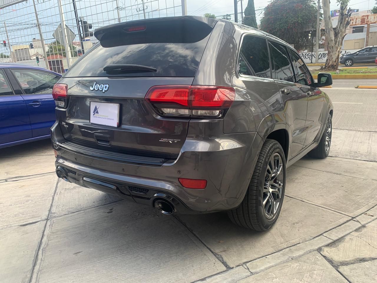 Jeep Grand Cherokee gris, vista trasera, estacionado en una acera.