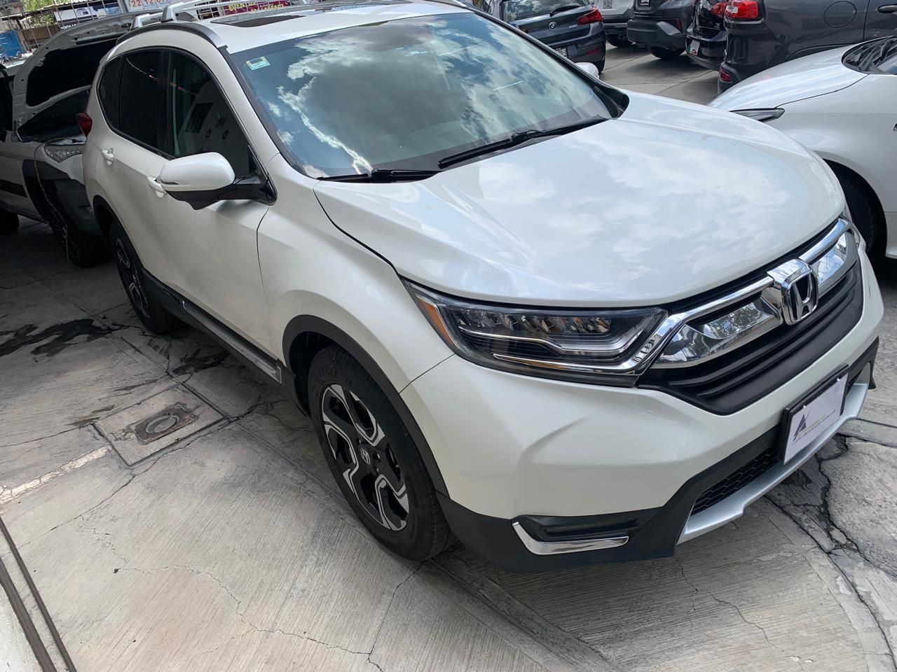 SUV Honda CR-V blanco estacionado en una superficie pavimentada, probablemente en un concesionario o estacionamiento de automóviles.