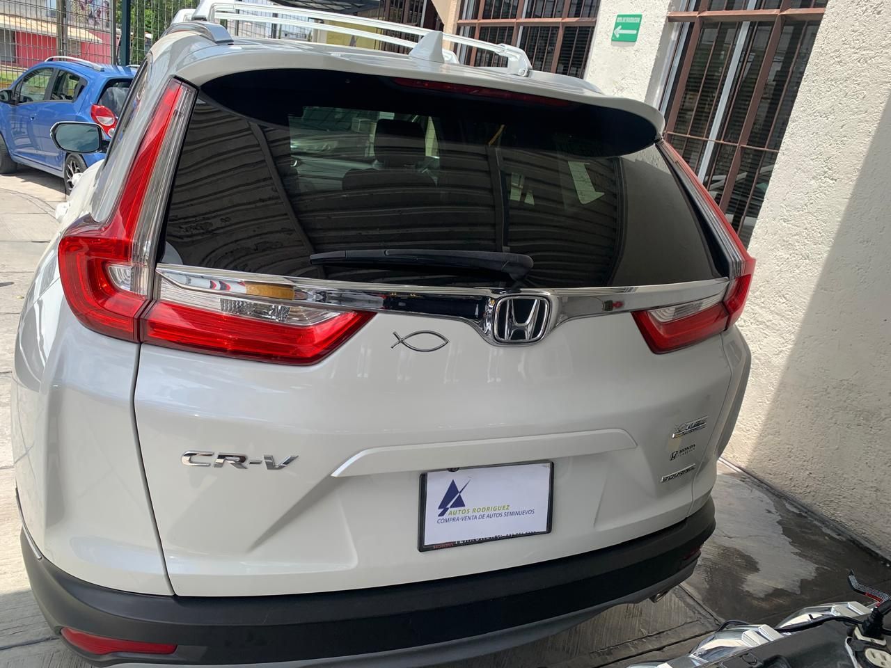 Honda CR-V SUV blanca estacionada, vista trasera. Molduras cromadas, portaequipajes y matrícula visibles.