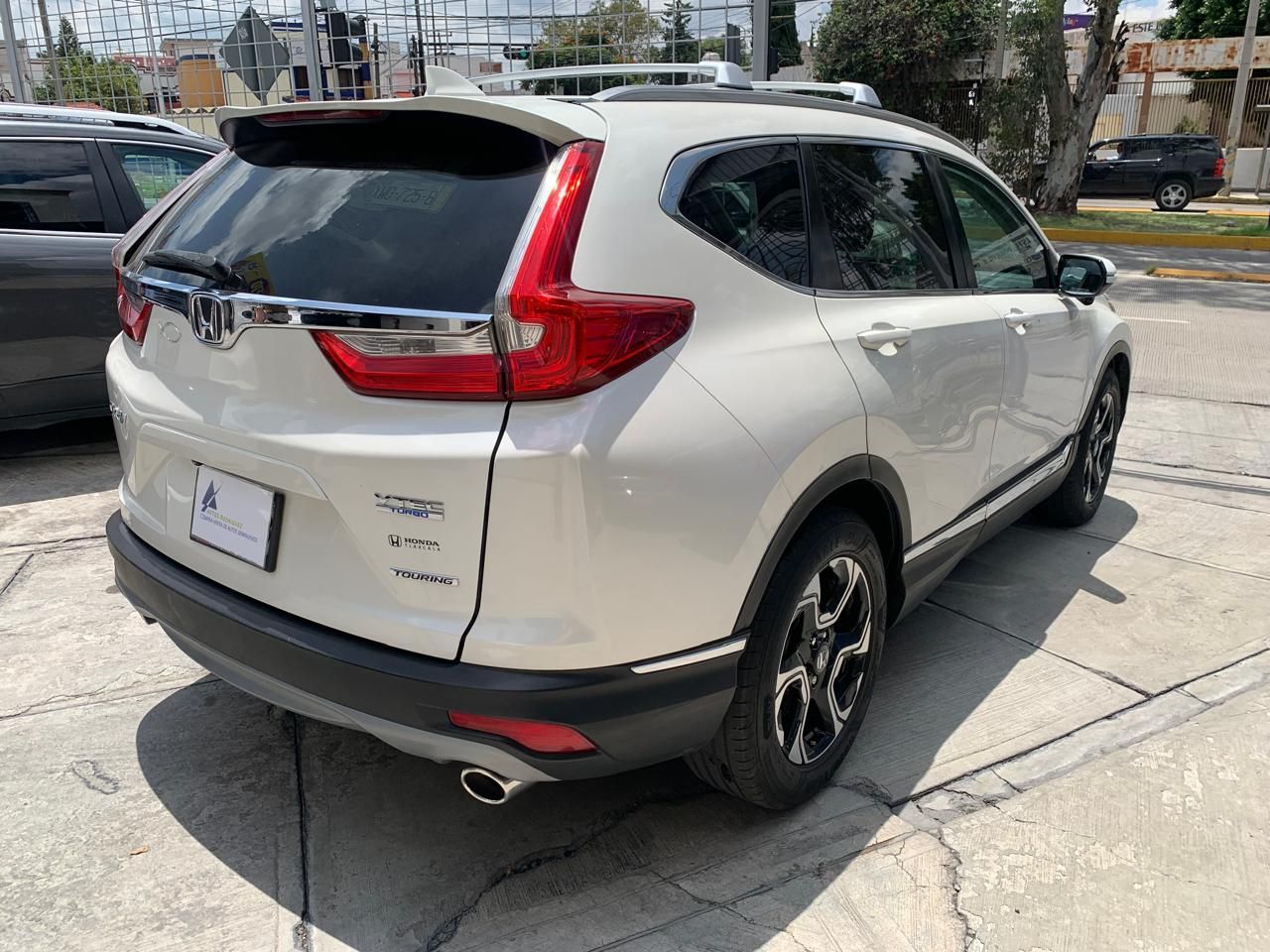 Honda CR-V SUV blanca estacionada al aire libre, vista en ángulo de la parte trasera. Detalles plateados y molduras negras.