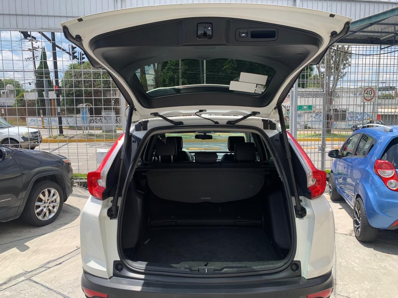 SUV blanca con el maletero abierto, estacionada en la calle. Interior visible: parte trasera y laterales, cubierta de carga negra.