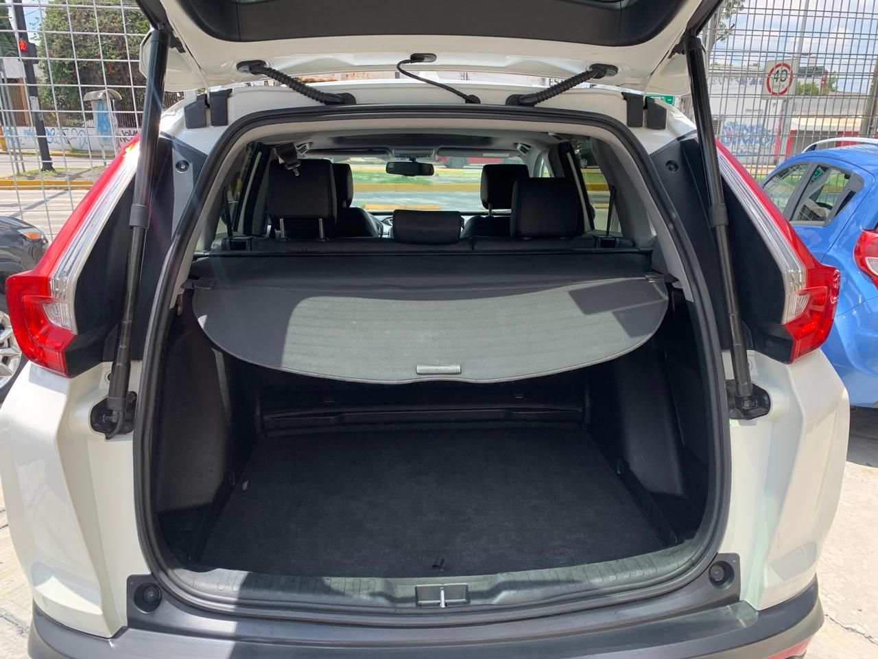 Baúl abierto de una SUV blanca con una cubierta de carga negra, revelando un espacio de carga vacío.