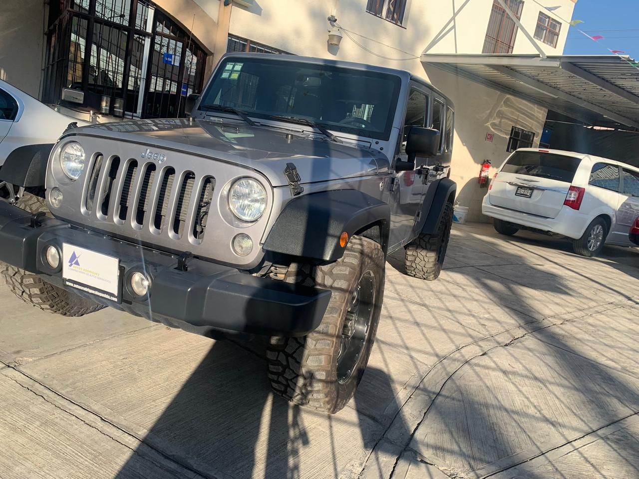 Jeep Wrangler gris estacionado sobre concreto.