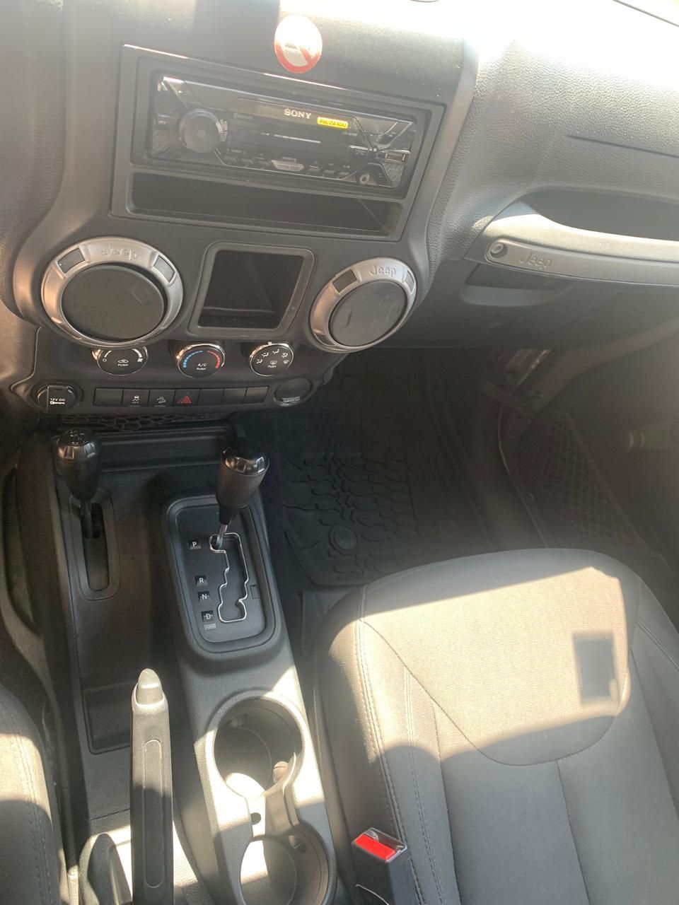 Interior de un Jeep Wrangler, que muestra el tablero, el estéreo, la palanca de cambios y los asientos.