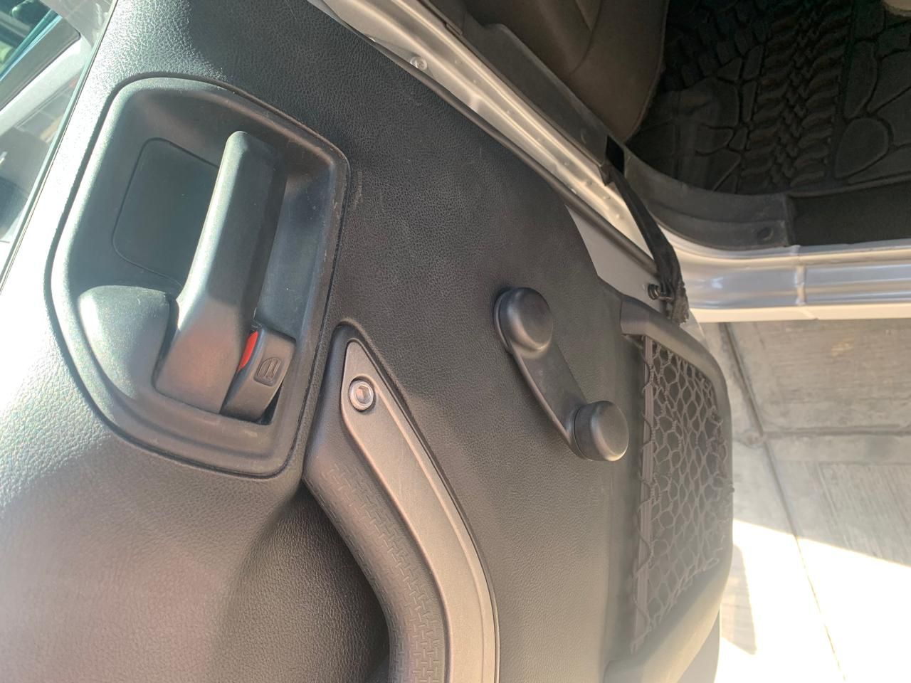 Panel interior de puerta de Jeep. Negro, con manija, manivelas para ventanillas y red de almacenamiento.