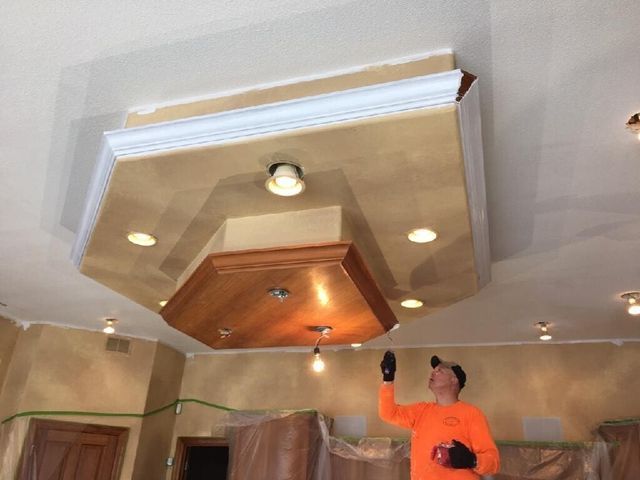 A man is painting the ceiling of a room.