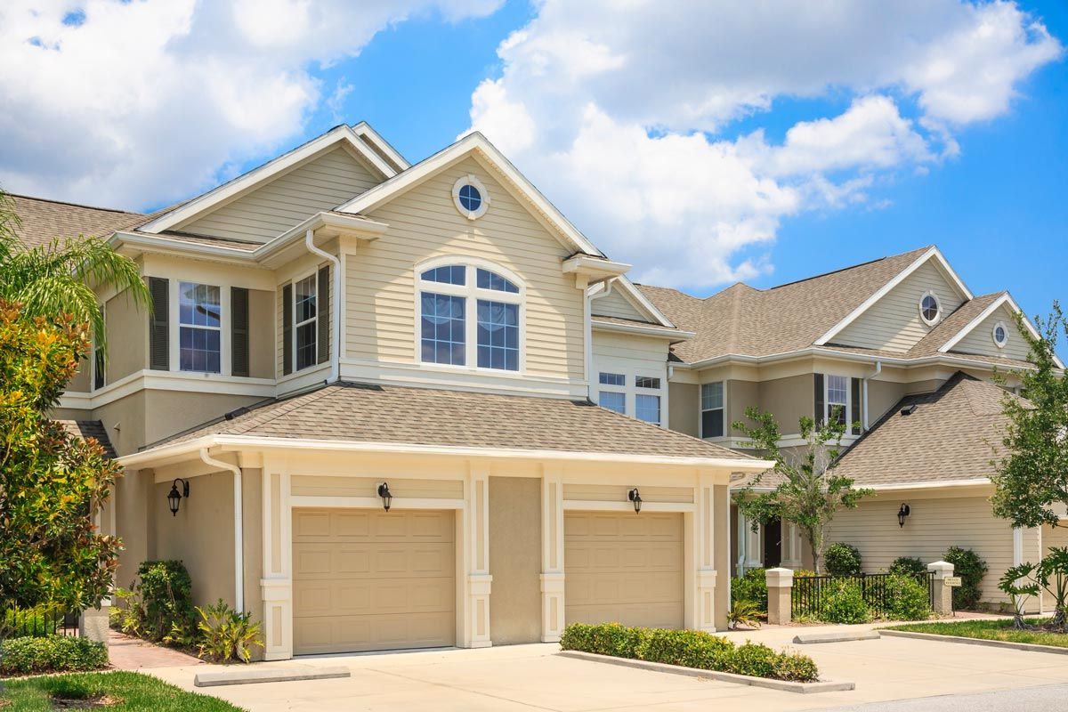 A large house with two garages and a blue sky in the background.