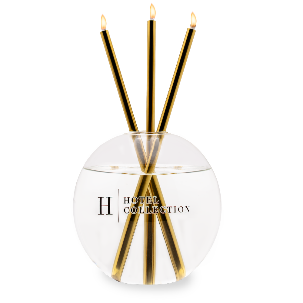 A candle in a glass container that says hotel collection