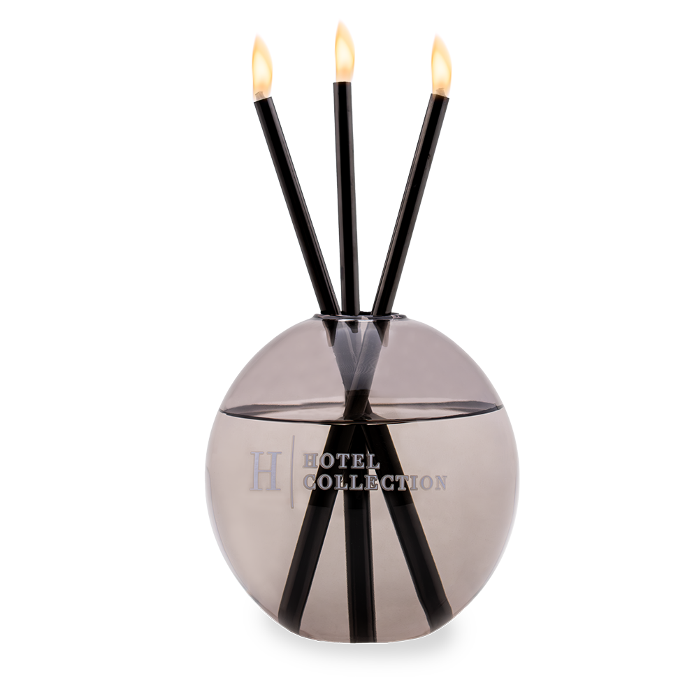 A hotel collection candle holder with three candles in it