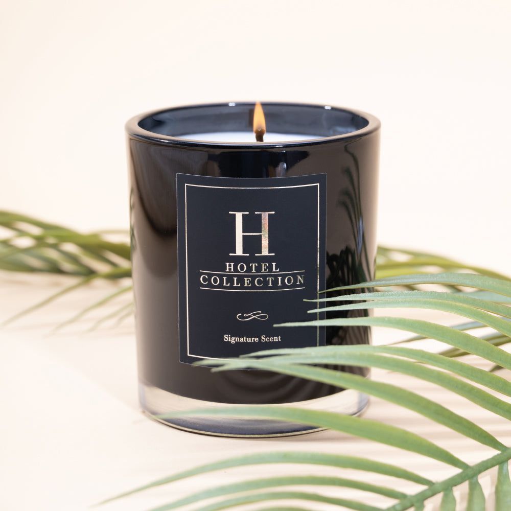 A black candle with a label that says hotel collection