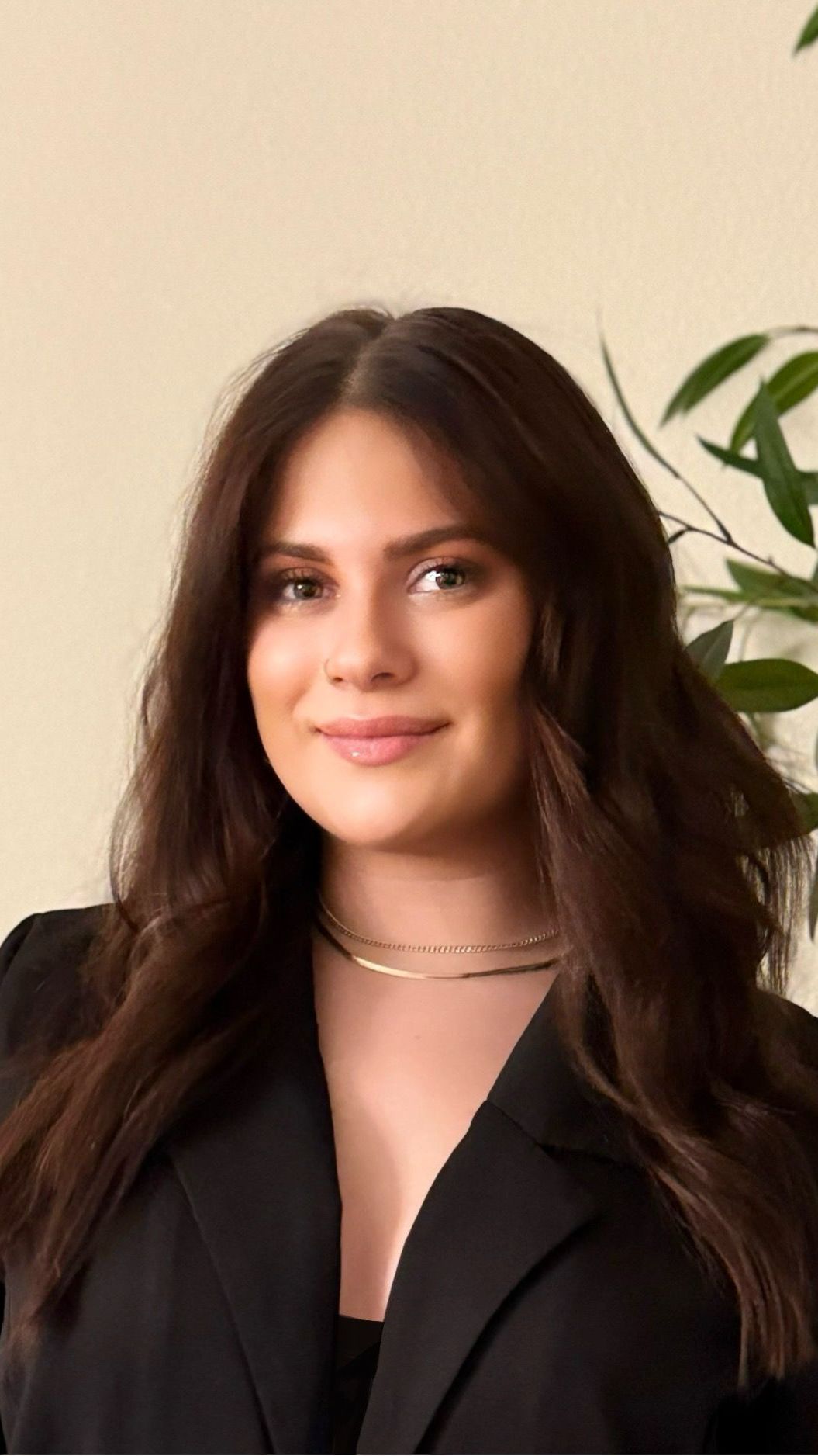 The woman is wearing a black jacket and a gold necklace.