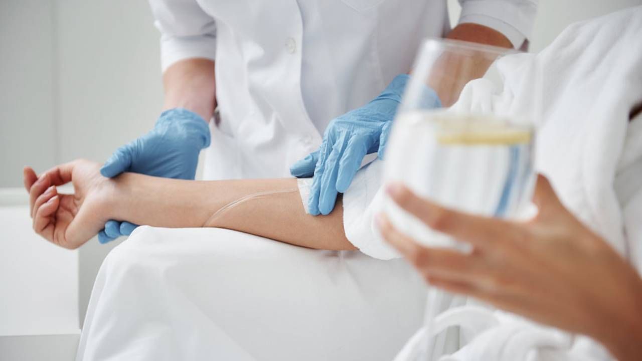 a woman is getting an injection in her arm while holding a glass of water .