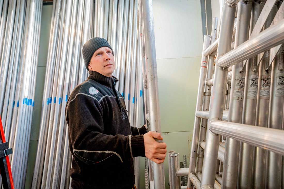 Mand i hue holder et metalstillads i et opbevaringsrum.