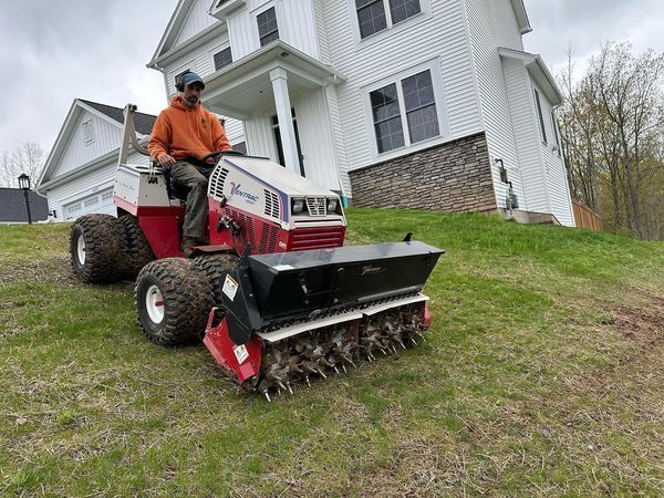 A man is riding a lawn mower in front of a house.