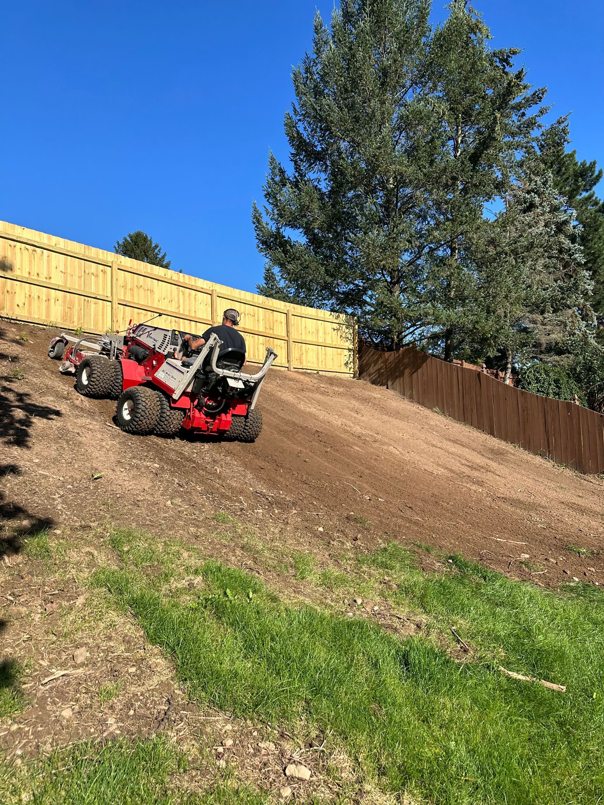 A man is riding a lawn mower down a hill.
