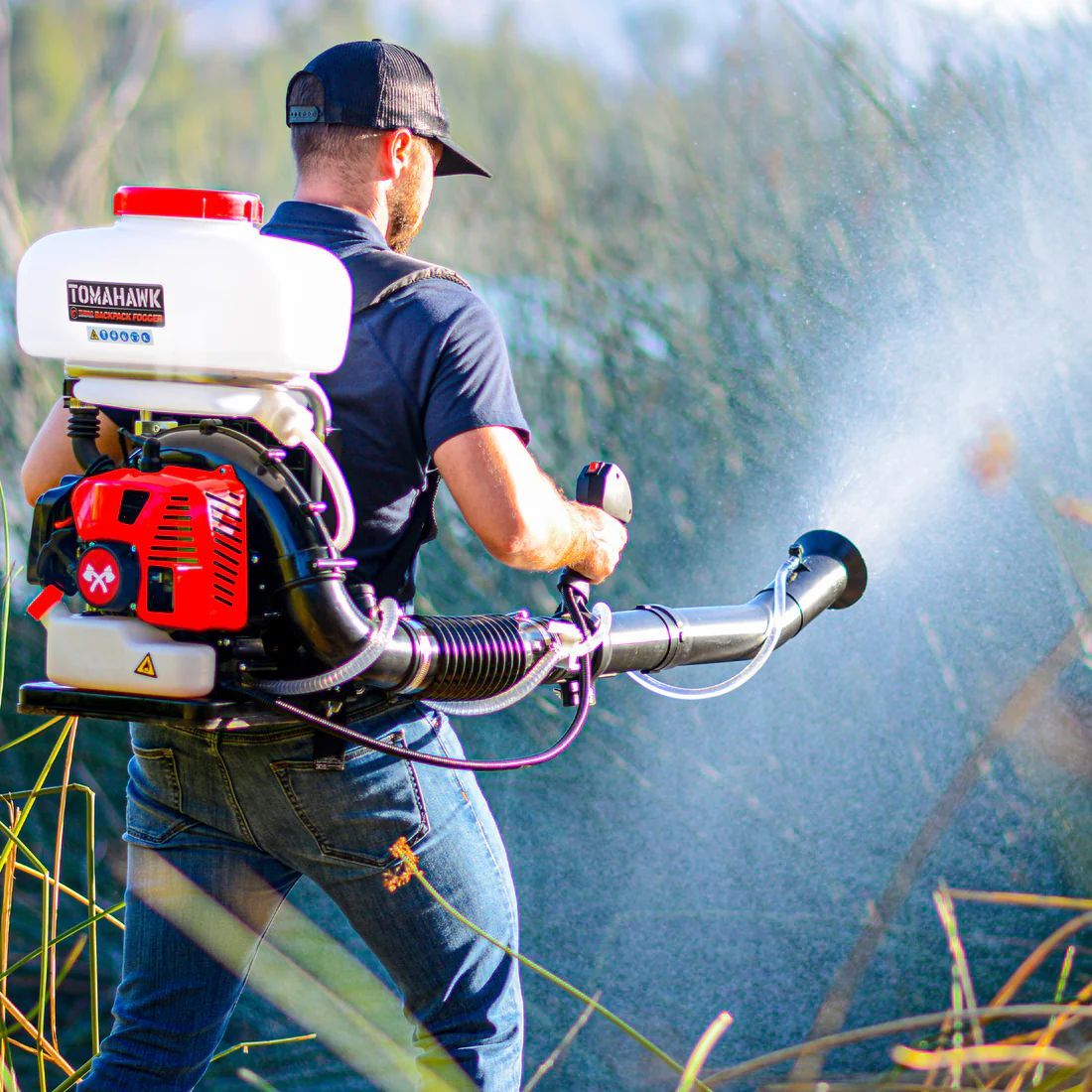 A man is spraying a lawn with a sprayer.