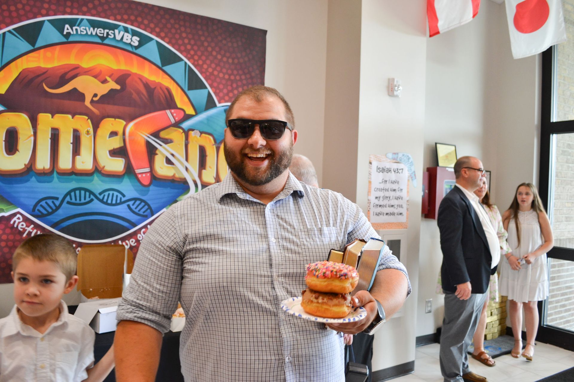 Man holding donuts, smiling, at event with a