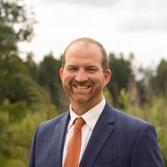 A man in a suit and tie is smiling for the camera.