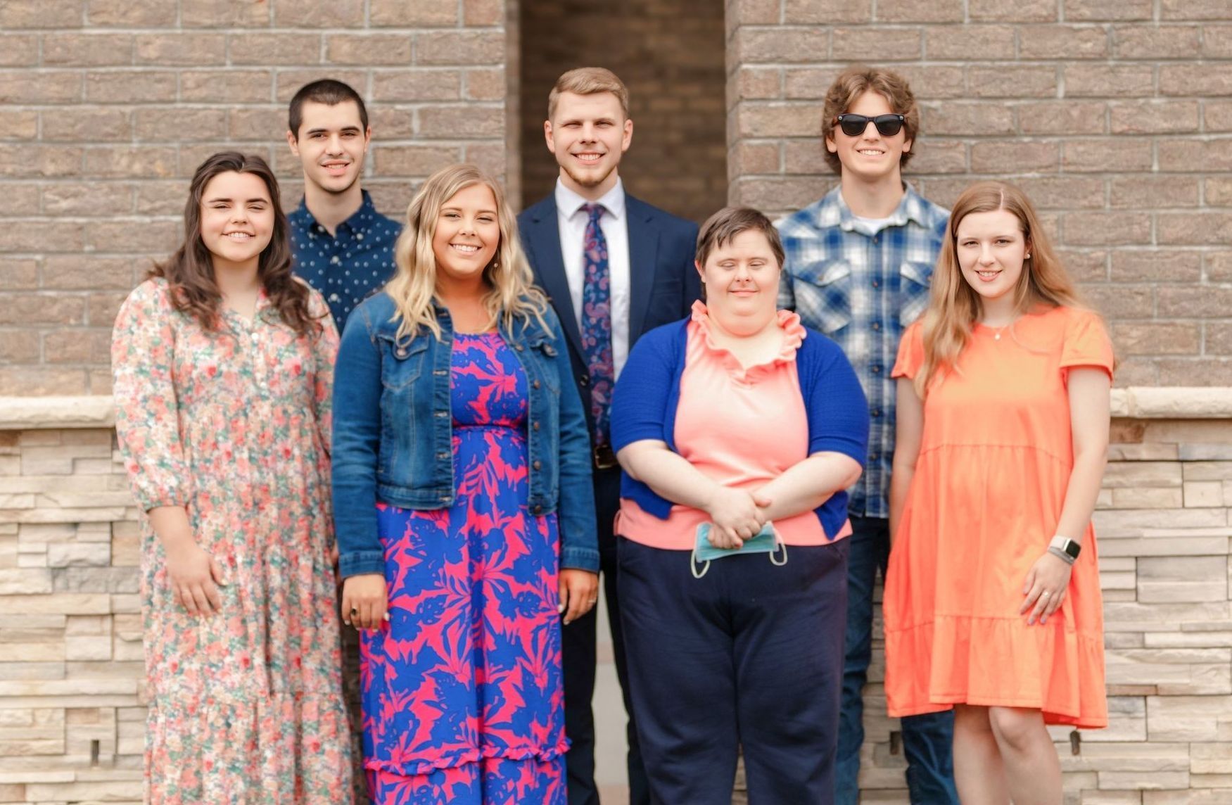 A group of people are posing for a picture in front of a brick building.