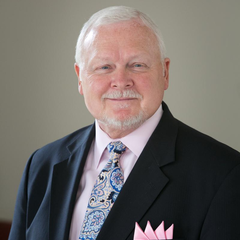 Pastor David Shaffer, wearing a paisley tie and pink pocket square, in front of a neutral backdrop.