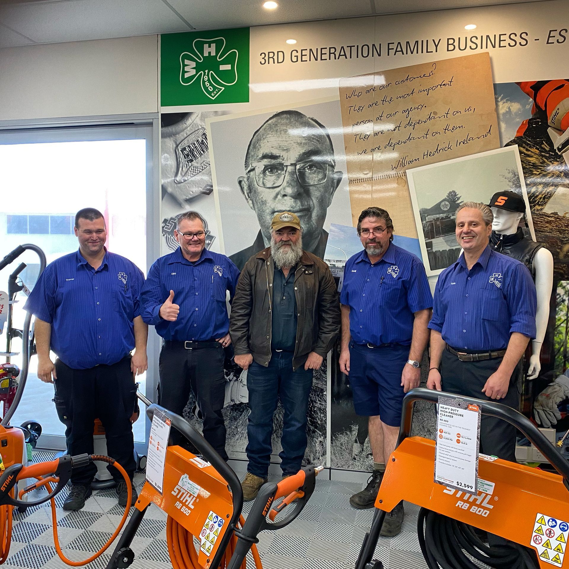 A Group of Men Are Posing for a Picture in Front of a Stihl Machine — Ireland's Machinery Pty Ltd In Braemar, NSW