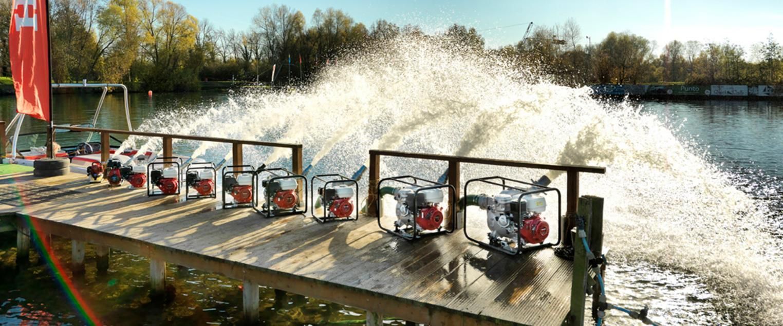 A Row of Water Pumps Are Sitting on a Wooden Dock Next to a Body of Water — Ireland's Machinery Pty Ltd In Braemar, NSW