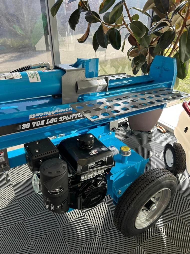 A Blue Log Splitter is Sitting on a Table Next to a Plant — Ireland's Machinery Pty Ltd In Braemar, NSW