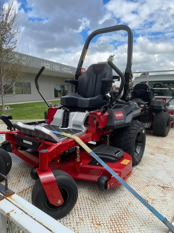 A Red Lawn Mower is Sitting on Top of a White Trailer — Ireland's Machinery Pty Ltd in Braemar, NSW