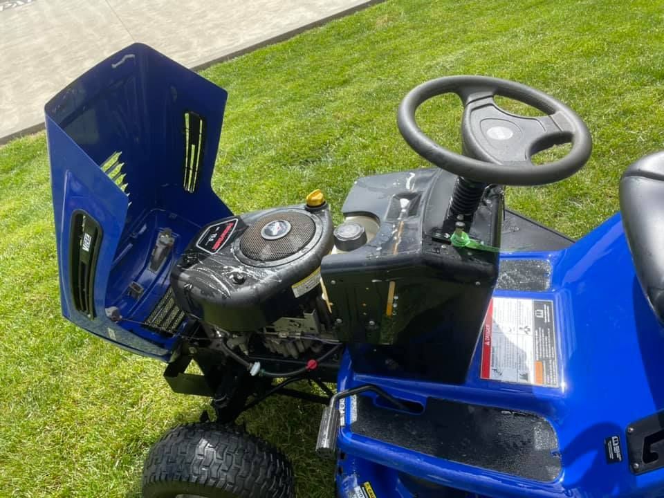A Blue Lawn Mower With the Hood Open is Parked in the Grass — Ireland's Machinery Pty Ltd in Braemar, NSW
