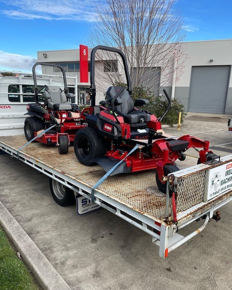 Two Lawn Mowers Are Sitting on Top of a Flatbed Trailer — Ireland's Machinery Pty Ltd in Braemar, NSW