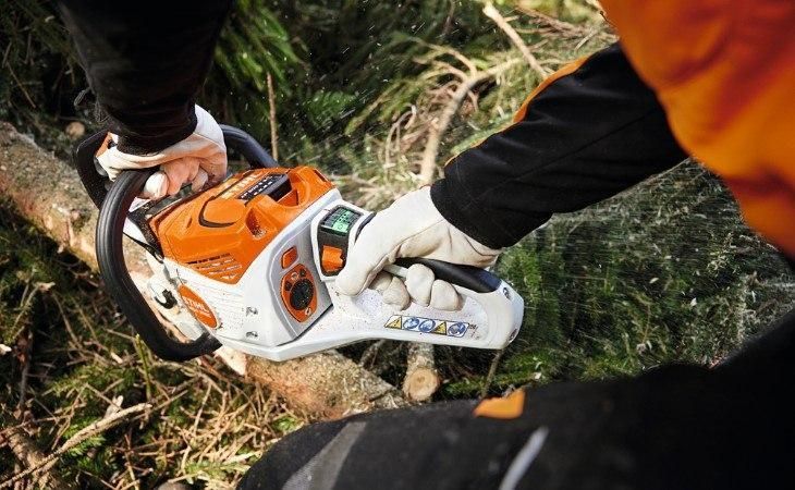 A Person is Using a Chainsaw to Cut a Tree Branch — Ireland's Machinery Pty Ltd In Braemar, NSW