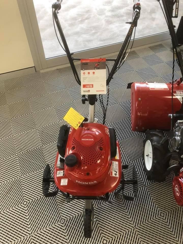 A Red Lawn Mower is Sitting on a Tiled Floor in a Showroom — Ireland's Machinery Pty Ltd In Braemar, Nsw