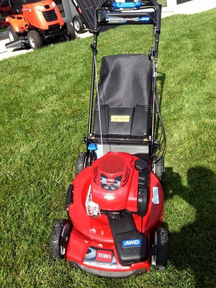 A Red Toro Lawn Mower is Sitting in the Grass — Ireland's Machinery Pty Ltd In Braemar, NSW