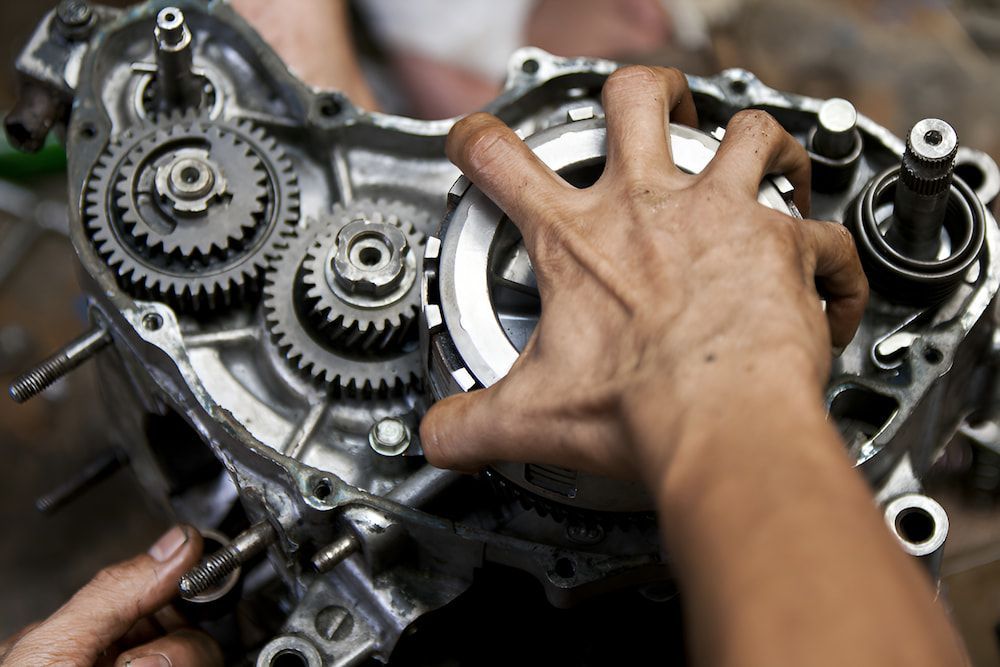 A Person is Working on a Motorcycle Engine With Their Hands — Ireland's Machinery Pty Ltd in Braemar, NSW