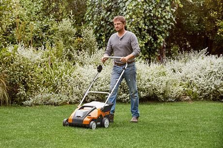 A Man is Using a Lawn Mower on a Lush Green Lawn — Ireland's Machinery Pty Ltd In Braemar, NSW