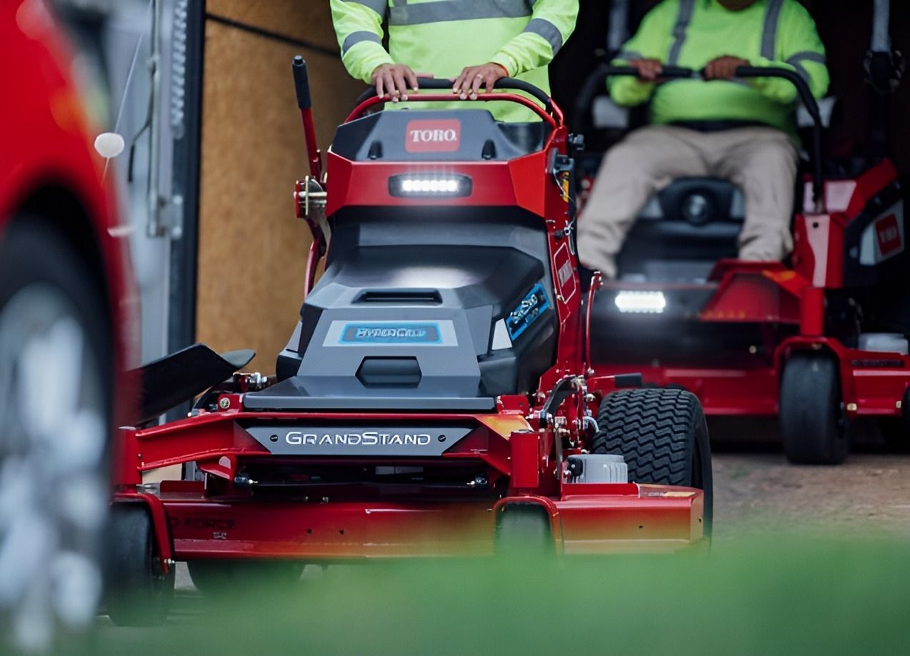 Two Men Are Riding Lawn Mowers in Front of a Truck — Ireland's Machinery Pty Ltd In Braemar, NSW