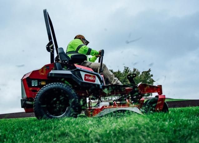 A Man is Riding a Lawn Mower on a Lush Green Field — Ireland's Machinery Pty Ltd In Braemar, NSW