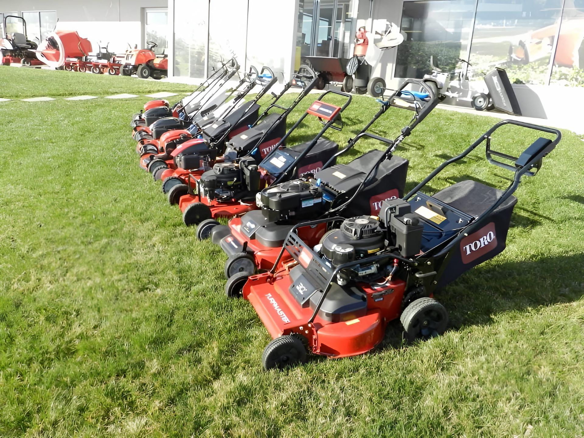 A ROw of Lawn Mowers Are Lined Up on a Lush Green Field — Ireland's Machinery Pty Ltd In Braemar, NSW