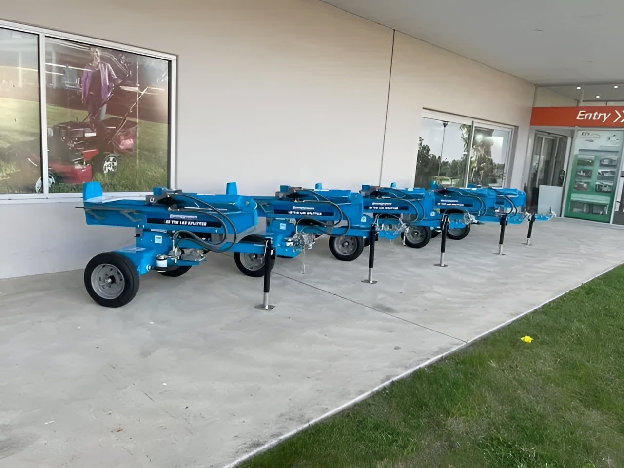A Row of Blue Log Splitter Machines Are Parked in Front of a Building — Ireland's Machinery Pty Ltd In Braemar, NSW