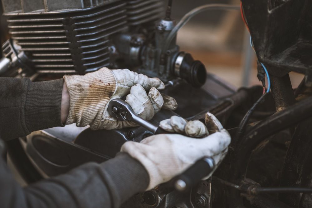A Person is Working on a Motorcycle With a Wrench — Ireland's Machinery Pty Ltd in Braemar, NSW