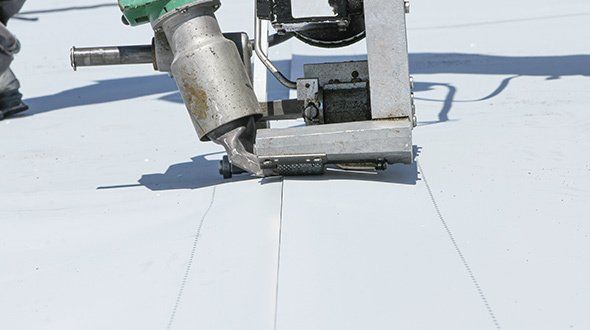 a person is using a machine to seal a roof .