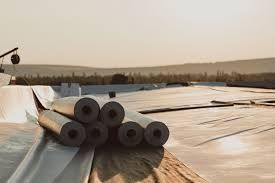 Rolls of roofing material are sitting on top of a roof under construction.