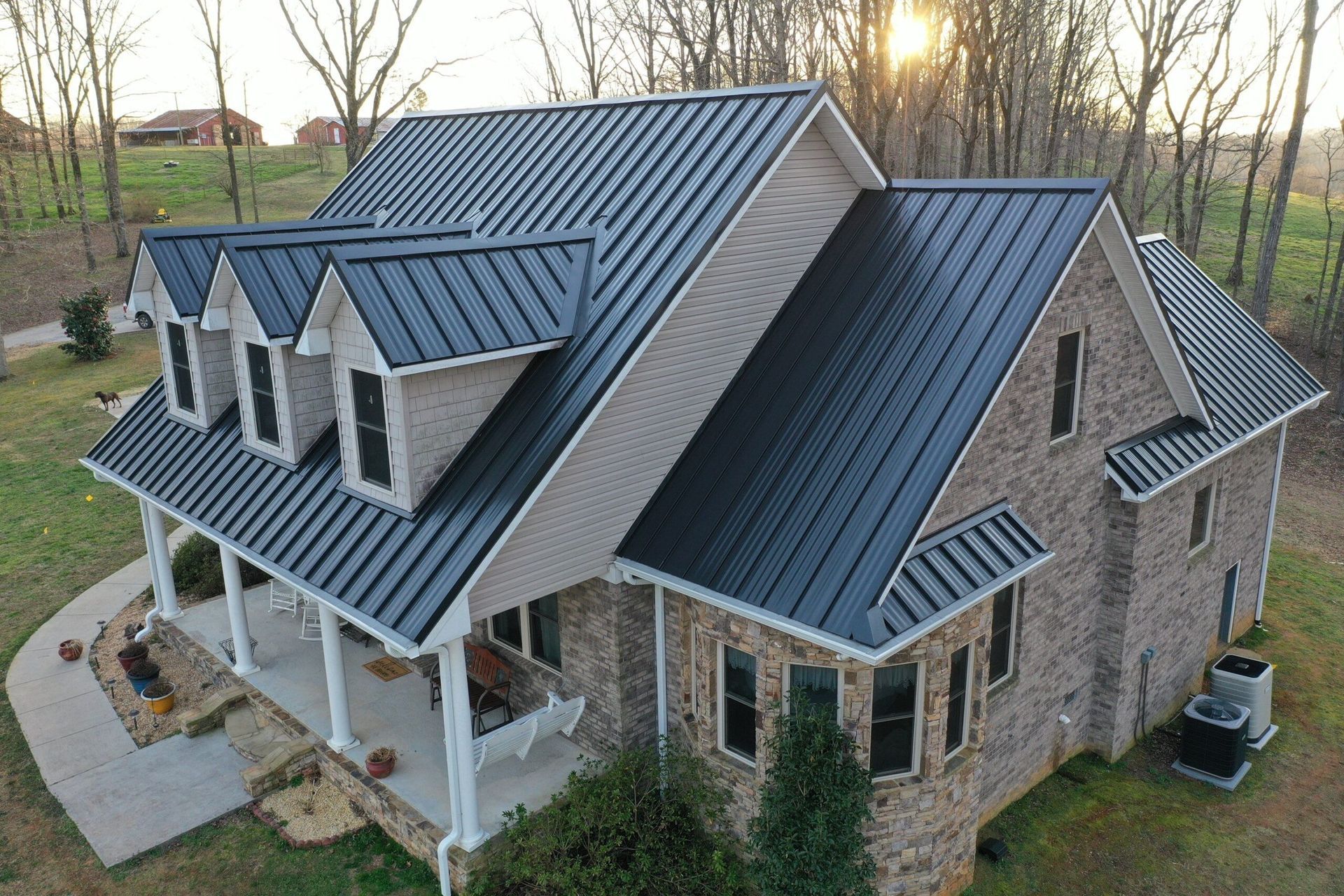 An aerial view of a large brick house with a black metal roof.