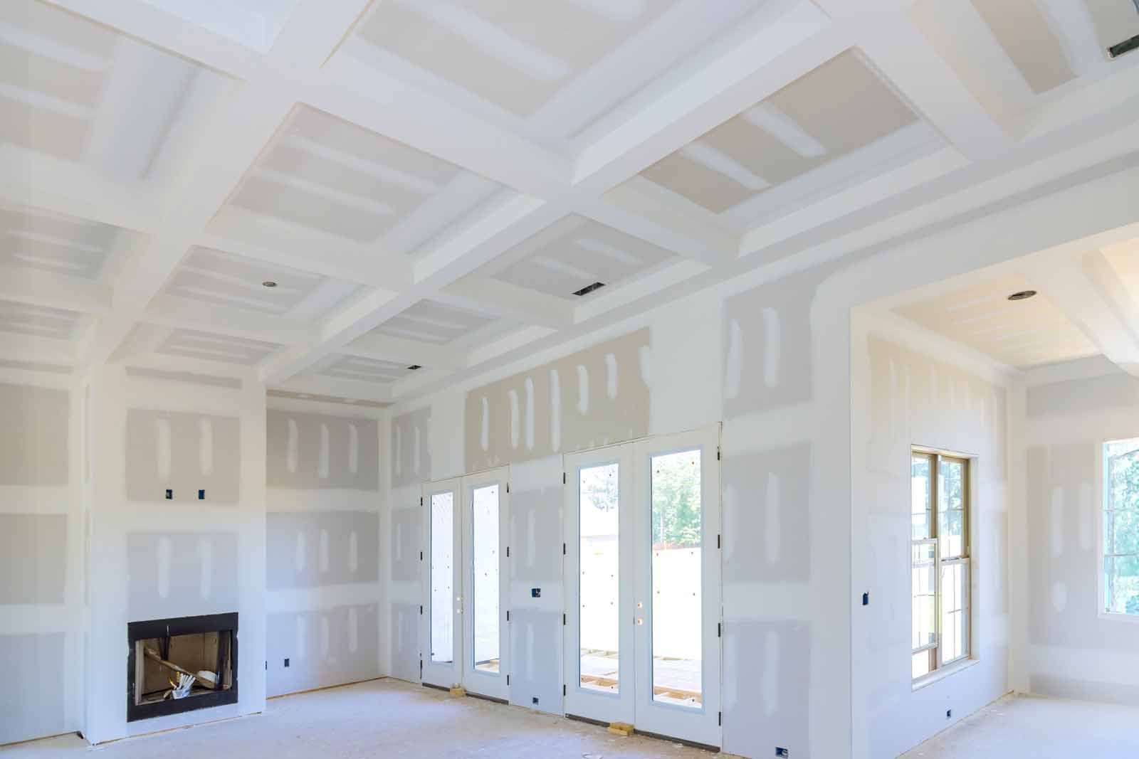 A living room in a house under construction with drywall on the walls and ceiling.