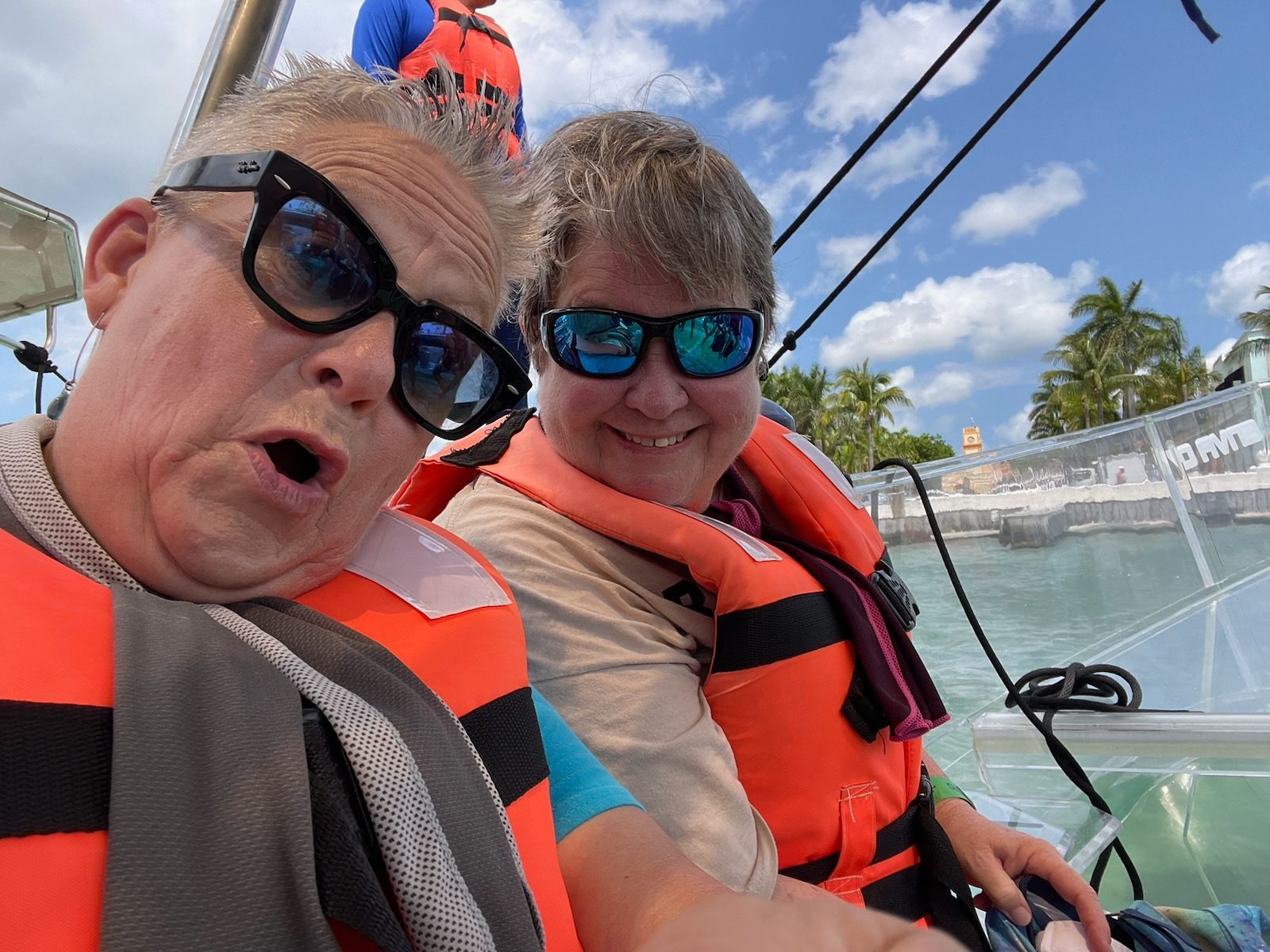 A man and a woman are sitting on a boat wearing life jackets.